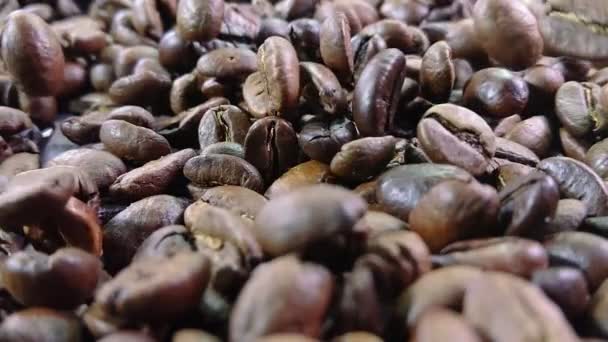 Närbild av rostade kaffebönor som faller på högen av kaffebönor — Stockvideo