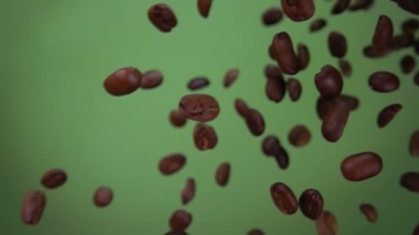 Смажені арабіки кавові зерна літають і обертаються на оливковому зеленому фоні — стокове відео