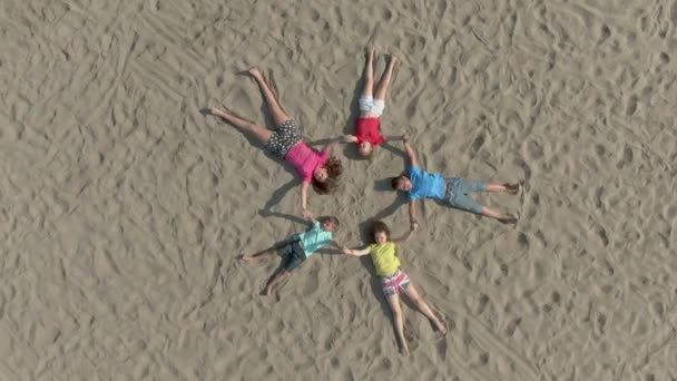 Rotonde luchtfoto 's van kinderen liggen op het zand in de vorm van een ster — Stockvideo