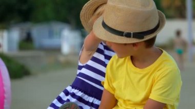 Küçük oğlan ve sevimli sarışın kız hasır şapkalarını çıkarıyorlar. 