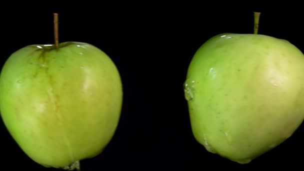 Groene appels vliegen en botsen op de zwarte achtergrond in slow motion — Stockvideo