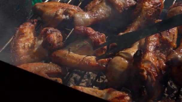 Vork draait de kippenpoten en vleugels op de grill over een open vuur — Stockvideo