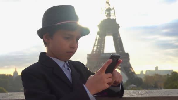Мальчик пишет сообщение по телефону на фоне Эйфелевой башни — стоковое видео