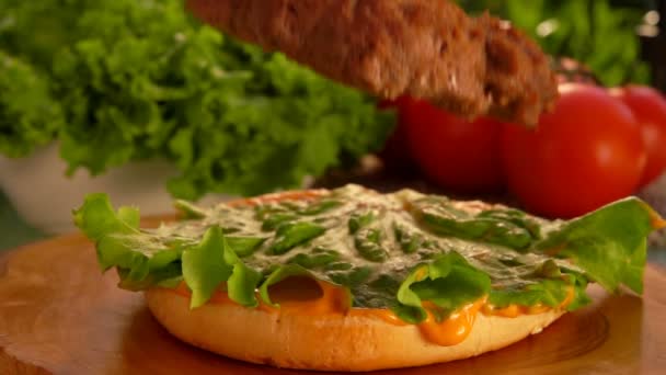 La cotoletta di manzo appetitosa sta cadendo sull'insalata verde e sul panino di hamburger. — Video Stock