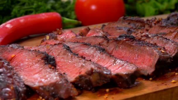 Sappig bereide biefstuk in plakjes gesneden op een houten plank met verse groenten — Stockvideo