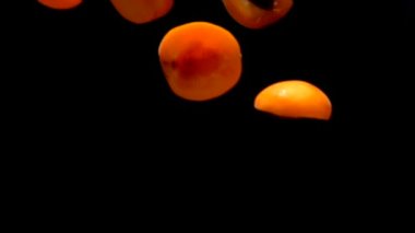 Yarım yamalak, olgun, sulu kayısılar siyah bir arkaplanda uçuyor.