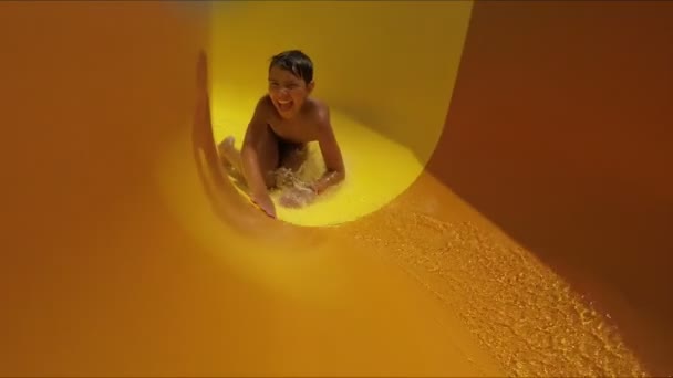 笑着的男孩在一个水上公园里乘坐橙色滑梯 — 图库视频影像