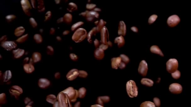 Los granos de café tostados Arabica están volando diagonalmente sobre un fondo negro — Vídeo de stock