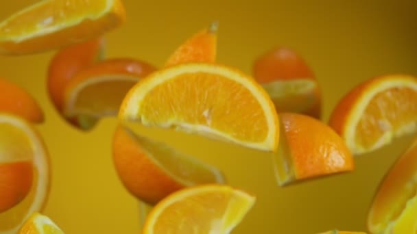 Jugosas rebanadas deliciosas de naranja madura vuelan sobre el fondo amarillo — Vídeo de stock