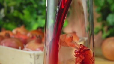 Nar suyu olgun nar dolu bir kutunun yanındaki sürahiye dökülür.