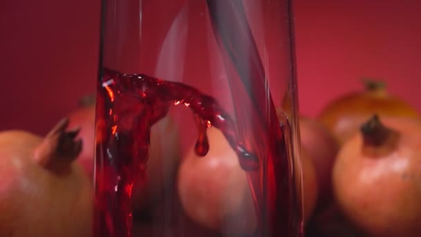 Onda di succo rosso scorre in una brocca sullo sfondo rosso di melograno — Video Stock