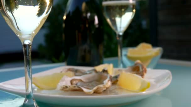 Copa de champán está de pie junto al plato blanco con ostras frescas abiertas — Vídeos de Stock