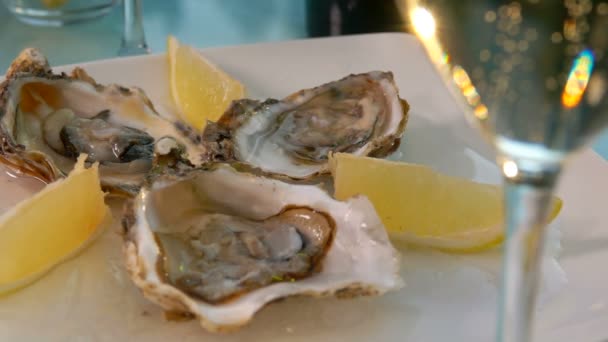 Primo piano di ostriche fresche aperte deliziose con limoni su un piatto bianco sul ghiaccio — Video Stock