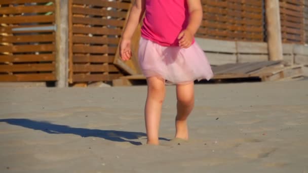 De lage hoek schieten van benen van klein meisje in roze runnung op het strand — Stockvideo