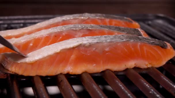 Cook flips a piece of delicious raw salmon steak with metal tongs — Stock Footage Cook flips a piece of delicious raw salmon steak with metal tongs Stock Footage