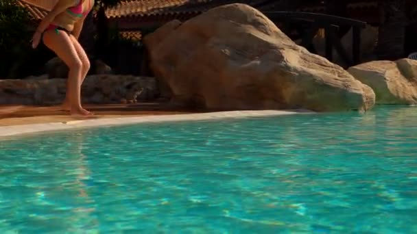 Діти в купальниках стрибають в басейн на відкритому повітрі — стокове відео