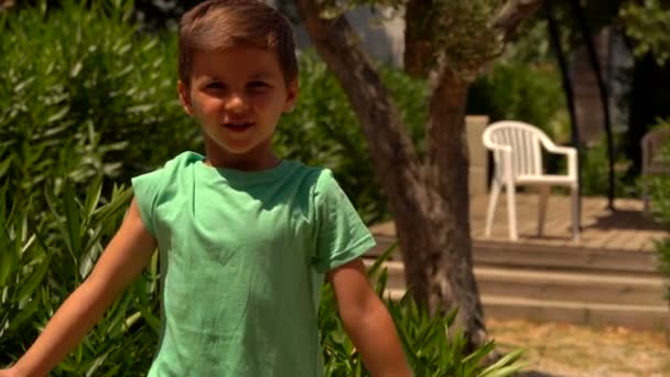 Liten glad pojke visar sina biceps muskler utomhus — Stockvideo