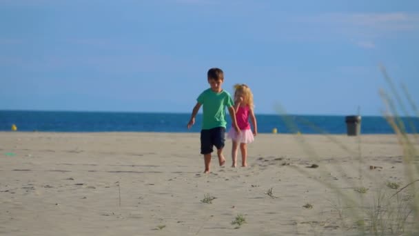 Liten pojke springer på stranden från den gråtande flickan till kameran och tillbaka — Stockvideo