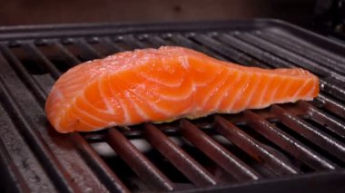 Lezzetli bir parça çiğ somon bifteği ızgarada kızarıyor.