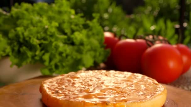 Folha de salada verde fresca está caindo sobre o pão de hambúrguer manchado com mostarda — Vídeo de Stock