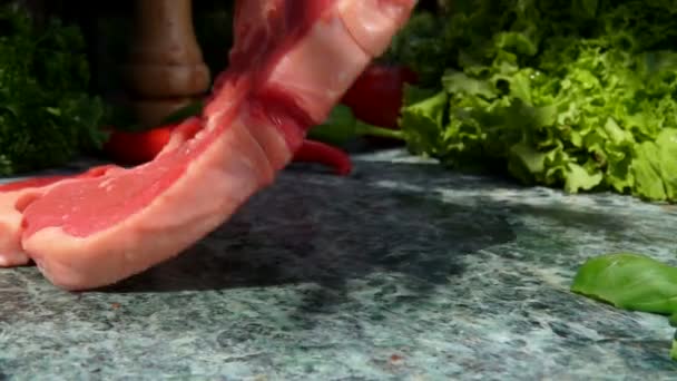 Bife cru está caindo em uma mesa de pedra no fundo de legumes frescos — Vídeo de Stock