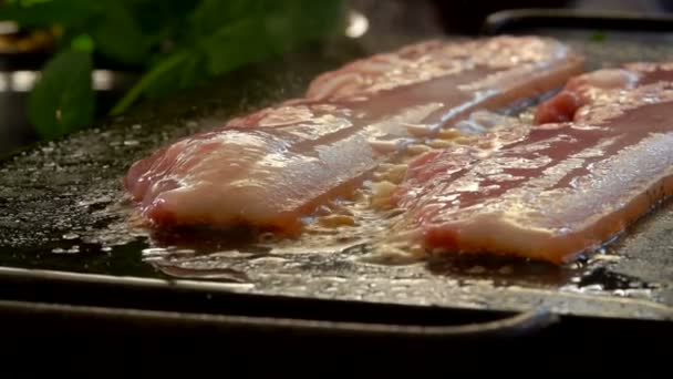 Super primer plano de las tiras de tocino tostado y chisporroteo en la parrilla plana — Vídeos de Stock