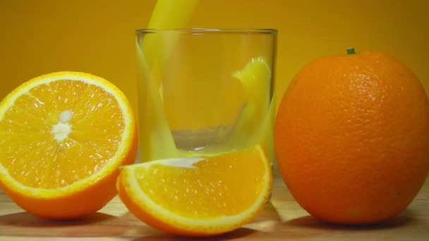 Вкусный апельсиновый сок наливают в стакан на желтом фоне — стоковое видео