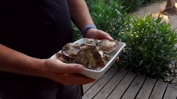 Un uomo che raccoglie una deliziosa ostrica fresca da un piatto quadrato bianco — Video Stock