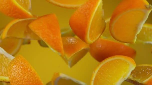 Auf dem gelben Hintergrund fliegen saftige Scheiben reifer Orangen auf und ab — Stockvideo