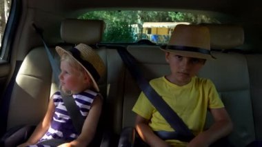Oğlan ve sarışın bir kız arabanın arka koltuğundalar. 