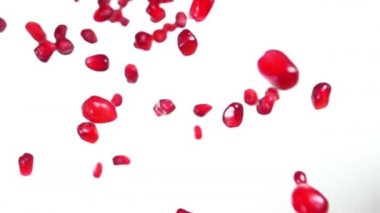 Ağız sulandıran nar taneleri beyaz arka planda çapraz olarak uçar.