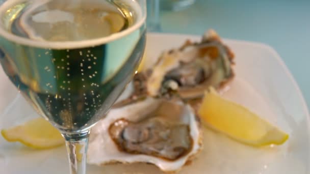 Close-up of champagne glass standing next to the plate with fresh open oysters — Stock Video