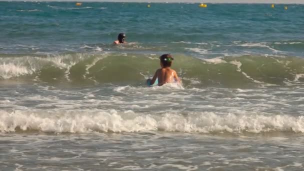 Çocuk yüzme tahtasıyla deniz dalgalarında zıplıyor. — Stok video