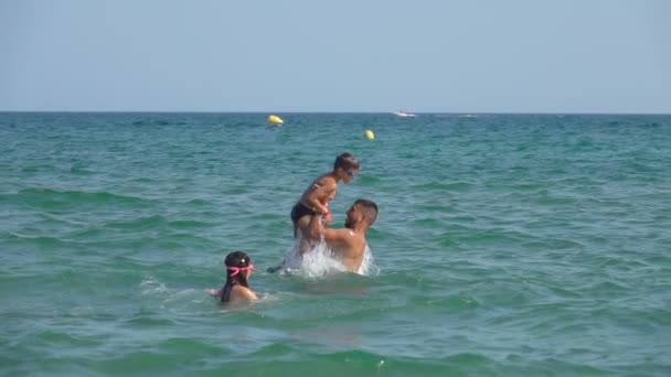 Jeune homme jette un petit garçon dans l'eau de mer avec une éclaboussure — Video