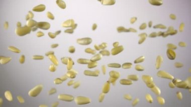 Beyaz arka planda zıplayan soyulmuş çam fıstıklarının yakın çekimi