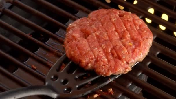 Кор перевертає котлет для чісбургера на гарячій поверхні решітки з спатулою. — стокове відео