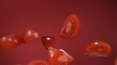 Kırmızı arkaplanda kırmızı sulu domates dilimleri uçuşuyor.