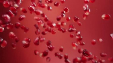 Sulu kırmızı nar taneleri kırmızı arkaplana çapraz düşüyor.