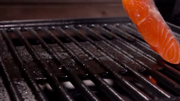 Cook coloca um pedaço de filé de salmão com pinças de metal na grelha — Vídeo de Stock