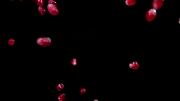 Sappige rode korrels rijpe granaatappel vliegen schuin op een zwarte achtergrond — Stockvideo