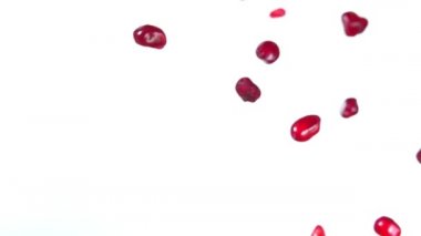 Olgun nar taneleri beyaz arka planda çapraz olarak uçuyor.