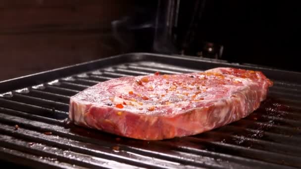 Filete crudo de carne deliciosa gruesa se fríe en la superficie caliente de la parrilla — Vídeo de stock