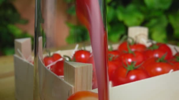 Ola de jugo de tomate fluye en una jarra de vidrio en el fondo de la vegetación — Vídeos de Stock