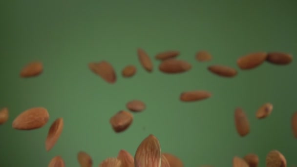 Крупним планом мигдаль відскакує і обертається на оливковому зеленому фоні — стокове відео
