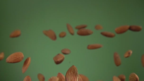 Gros plan des amandes qui rebondissent et tournent sur le fond vert olive — Video