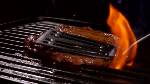 Толстый мясной стейк посыпанный специями жарится на горячей поверхности гриля — стоковое видео