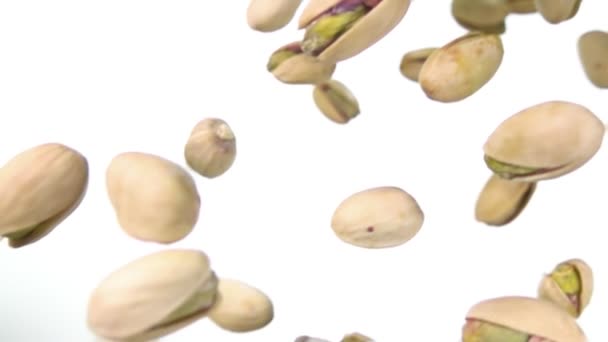 Primer plano de pistachos asados volando y girando sobre fondo blanco — Vídeo de stock