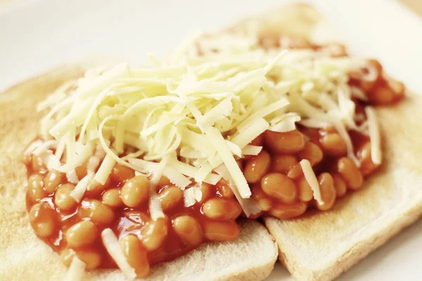 Baked beans on white toast topped with grated cheddar cheese - filter applied