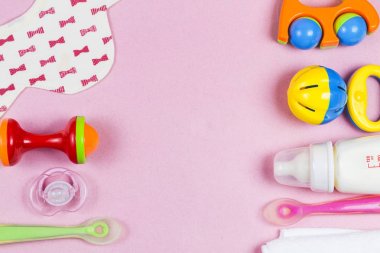 Bebek aksesuarları. Ahşap oyuncak, emzik ve biberon pembe backg üzerinde