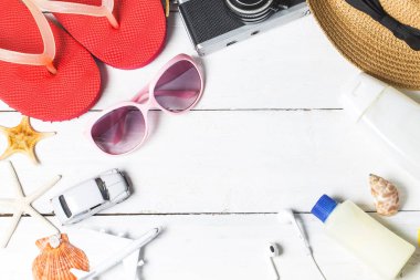 Plaj aksesuarları. Çanta, havlu, güneş gözlüğü ve ahşap arka plan üzerinde parmak arası terlik. Kopya alanı ile Üstten Görünüm